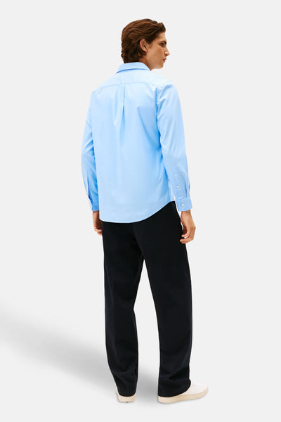 Chemise à manches longues bleue de TOMMY HILFIGER, portée avec un pantalon foncé et des baskets blanches, vue de dos.