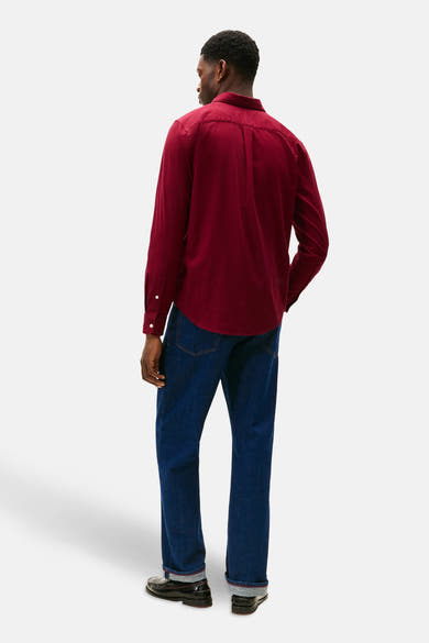 Chemise bordeaux à manches longues de TOMMY HILFIGER, avec fermeture boutonnée, portée avec un jean bleu foncé.