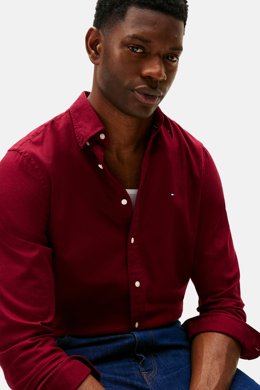 Chemise bordeaux à manches longues de TOMMY HILFIGER, partiellement boutonnée, portée avec un débardeur blanc et un jean bleu foncé.