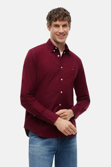 Chemise bordeaux à manches longues par TOMMY HILFIGER, boutonnée avec col classique, portée avec jeans bleus, vue de face