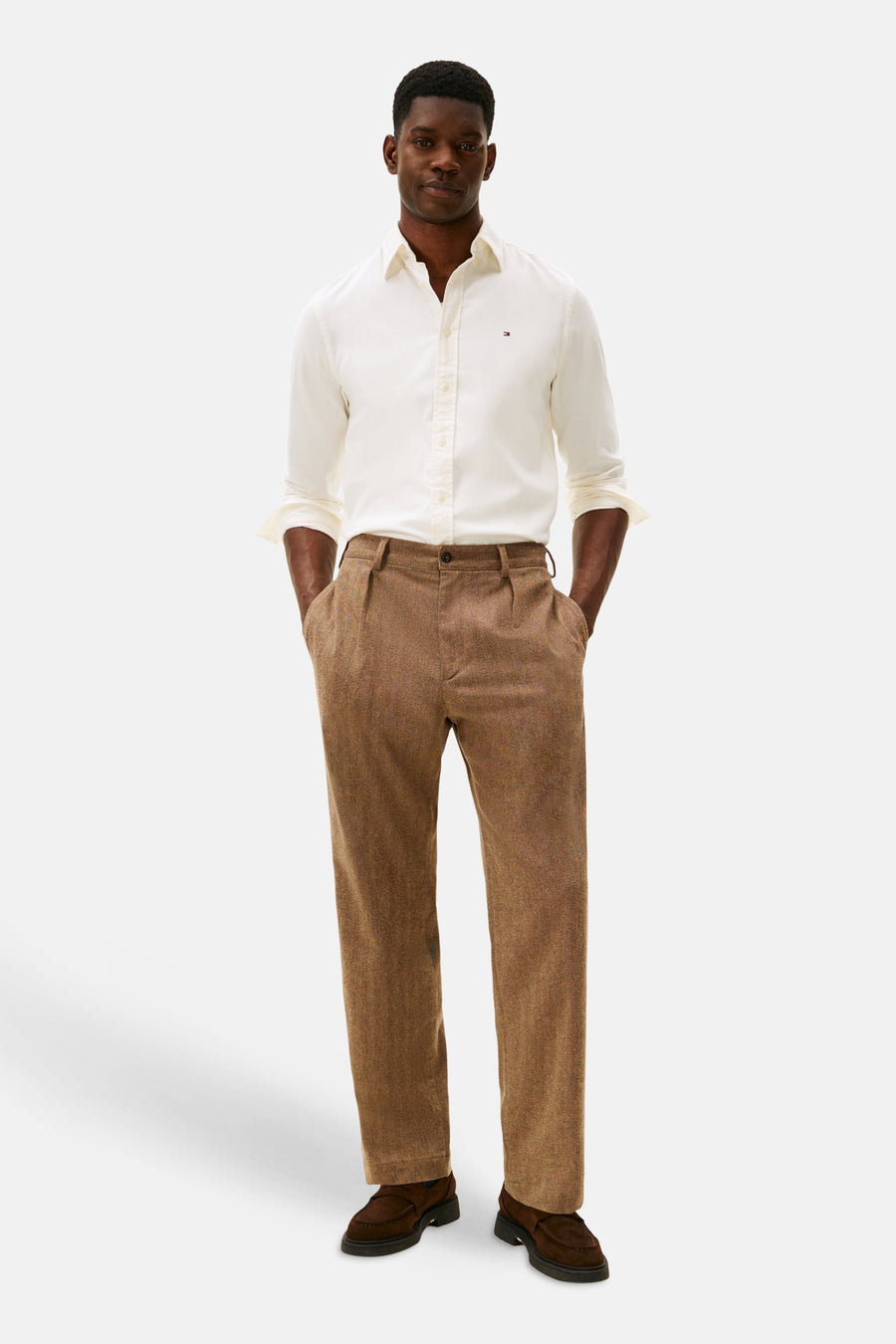 Chemise à manches longues écru de TOMMY HILFIGER, portée avec un pantalon marron à chevrons et des chaussures loafers.