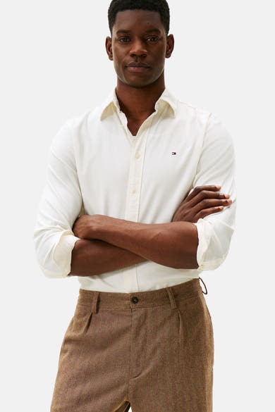 Chemise à manches longues écru de TOMMY HILFIGER, avec manches retroussées et pantalon marron à chevrons.