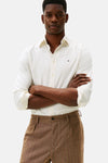 Chemise à manches longues écru de TOMMY HILFIGER, avec manches retroussées et pantalon marron à chevrons.