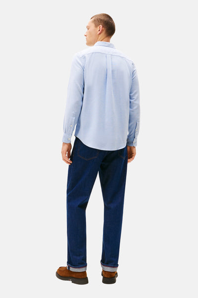 Blauwe blouse met lange mouwen van TOMMY HILFIGER, met knopen, gedragen met een spijkerbroek en bruine schoenen.