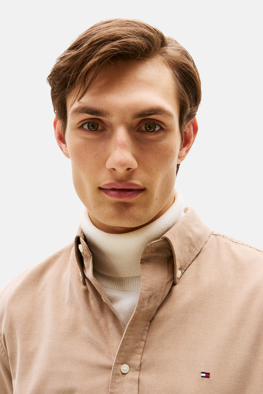 Beige ribfluwelen hemd van Tommy Hilfiger, gedragen met een witte coltrui.