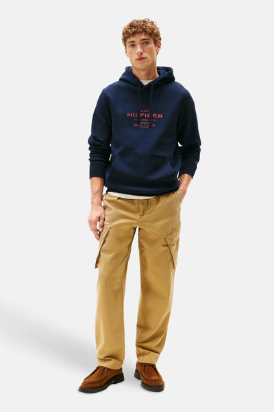 Blauwe Tommy Hilfiger hoodie, gedragen met een wit T-shirt en een bruine cargobroek.
