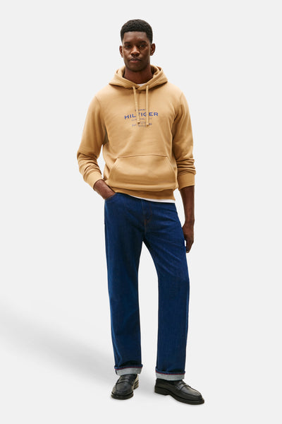 Beige hoodie van TOMMY HILFIGER, gedragen met een wijde jeans en zwarte schoenen.
