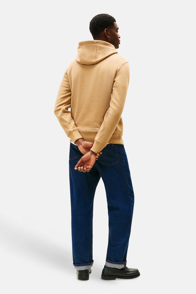 Beige hoodie van TOMMY HILFIGER, gedragen met een blauwe jeans en zwarte loafers, achterzicht.