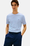 T-shirt bleu à rayures, de Tommy Hilfiger, avec un logo discret sur la poitrine, porté avec un pantalon bleu marine.