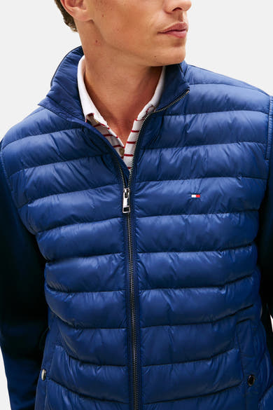 Veste bleue de TOMMY HILFIGER, matelassée avec fermeture éclair, portée sur une chemise rayée.