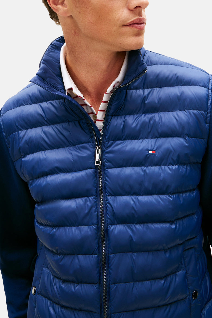 Veste bleue de TOMMY HILFIGER, matelassée avec fermeture éclair, portée sur une chemise rayée.