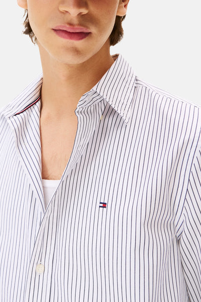 Chemise rayée blanche à manches longues de TOMMY HILFIGER, avec le logo distinctif et une doublure rouge subtile.