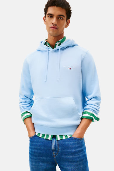 Blauwe hoodie van TOMMY HILFIGER, gedragen met een groen-wit gestreept overhemd en een spijkerbroek.