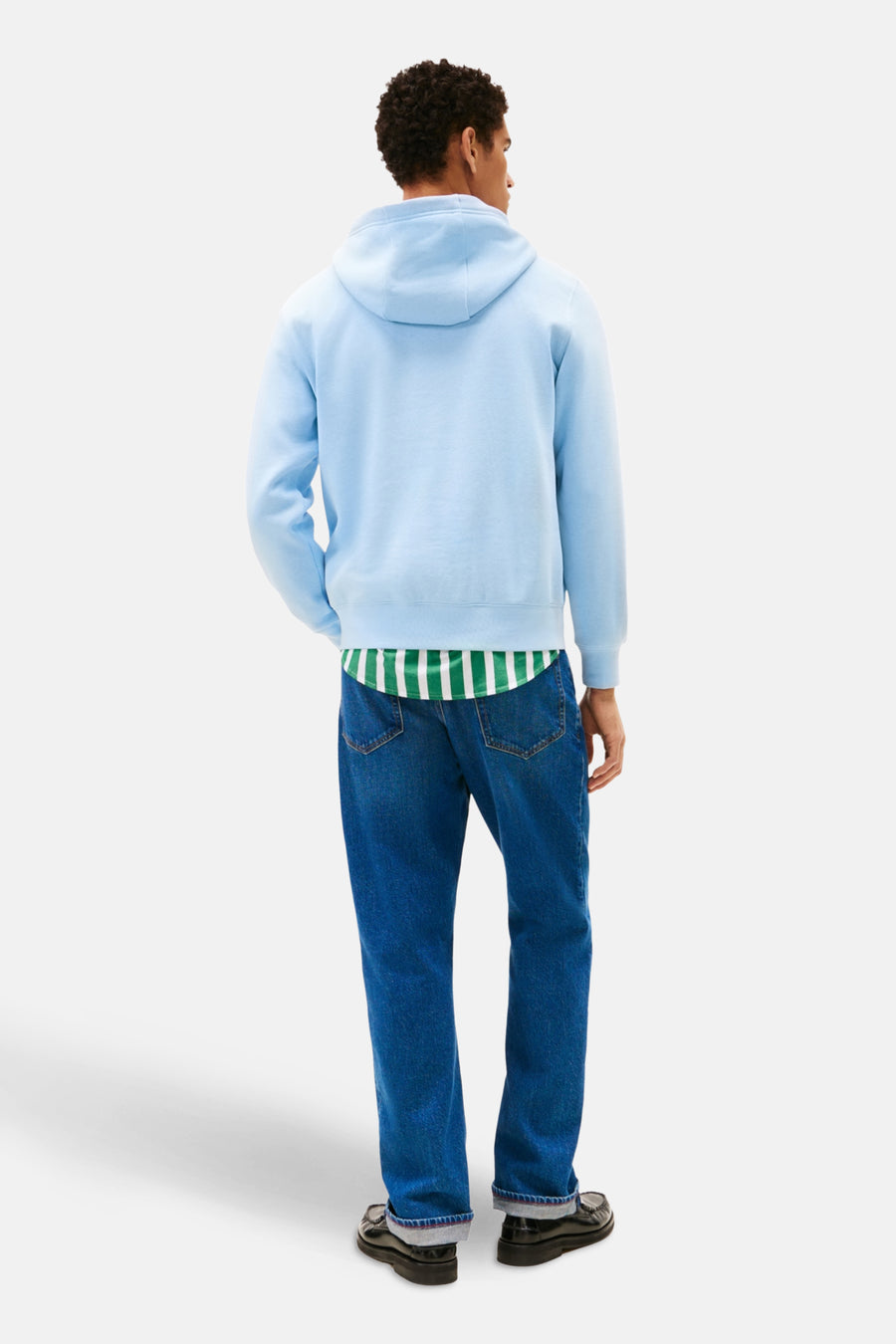 Sweat à capuche bleu de TOMMY HILFIGER, porté avec une chemise rayée verte et blanche et un jean bleu.