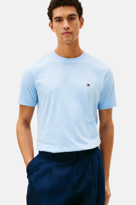T-shirt bleu à manches courtes de TOMMY HILFIGER, porté avec un pantalon marine plissé.