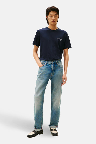 T-shirt à manches courtes bleu de TOMMY HILFIGER, porté avec un jean délavé et des mocassins bicolores.