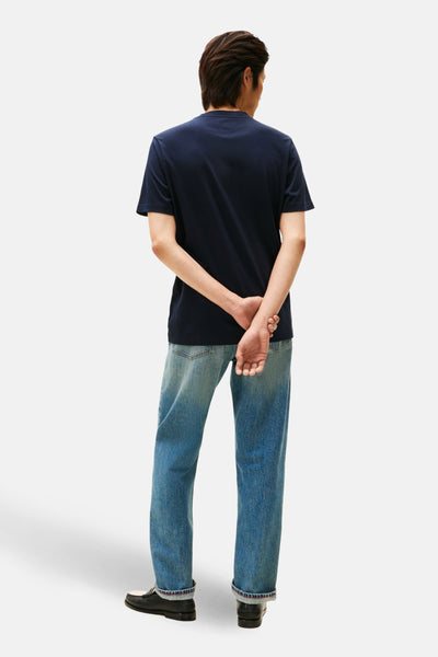 T-shirt à manches courtes bleu de TOMMY HILFIGER, porté avec un jean délavé et des mocassins noirs, vue de dos.