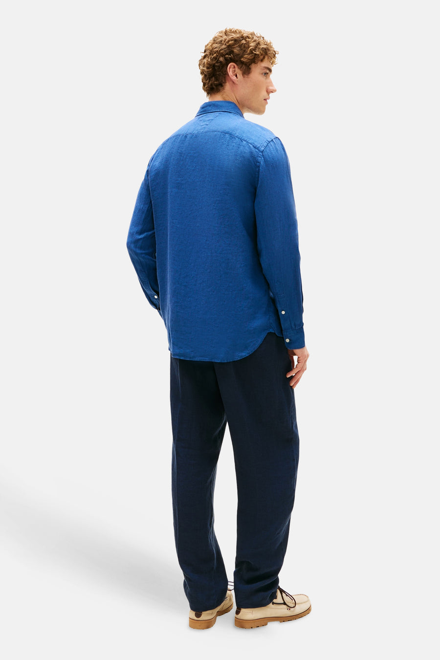 Blauwe blouse met lange mouwen van TOMMY HILFIGER, gedragen met een wijde marineblauwe broek en beige bootschoenen.