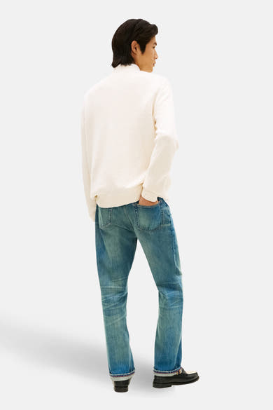 Pull à col rond en coton écru de TOMMY HILFIGER, porté avec un jean bleu et des mocassins noirs, vue de dos.