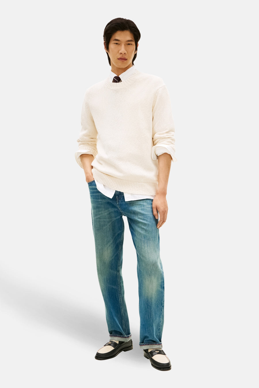 Pull à col rond écru de TOMMY HILFIGER, porté avec une chemise blanche et un pantalon en jean.