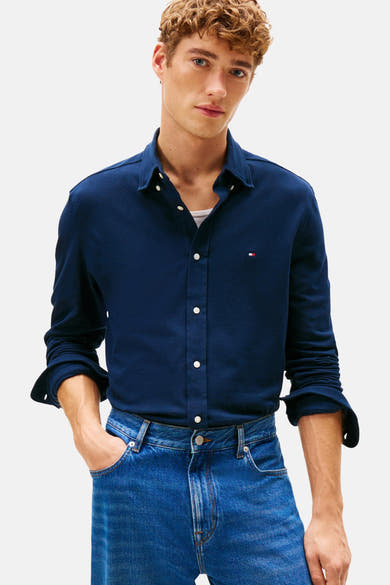 Chemise à manches longues bleue de TOMMY HILFIGER, portée avec un jean et un t-shirt blanc.