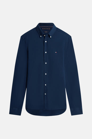 Chemise bleu marine à manches longues de TOMMY HILFIGER avec une boutonnière blanche et le logo sur la poitrine.