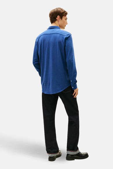 Chemise à manches longues bleue de TOMMY HILFIGER, portée avec un jean foncé et des mocassins noirs, vue de dos.