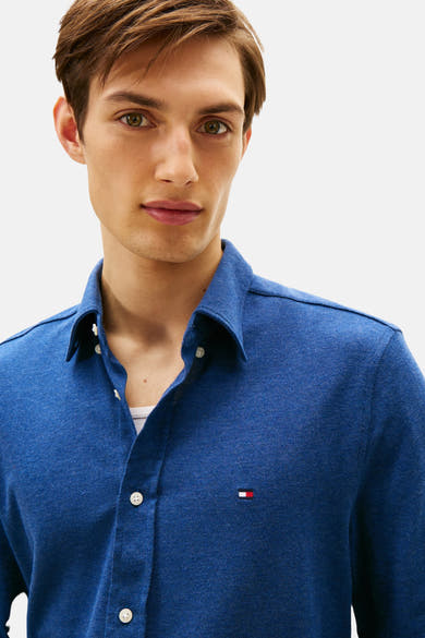 Chemise à manches longues bleue de Tommy Hilfiger, avec boutons blancs et logo sur la poitrine.