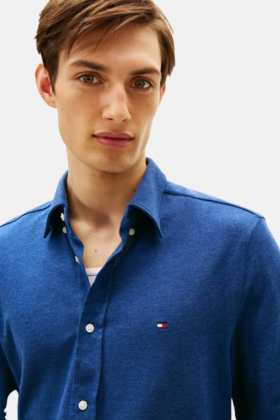Chemise à manches longues bleue de Tommy Hilfiger, avec boutons blancs et logo sur la poitrine.