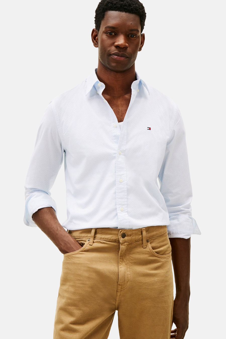 Chemise à manches longues bleue de TOMMY HILFIGER, à motif discret, portée avec un pantalon chino marron.