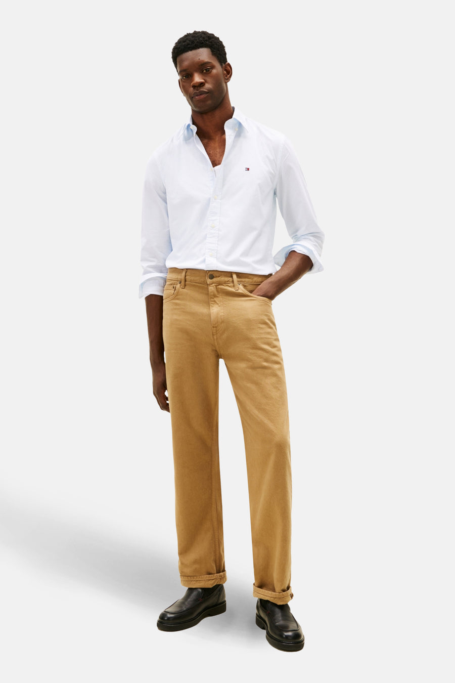 Chemise à manches longues bleue de TOMMY HILFIGER, portée avec un pantalon marron et des chaussures noires.