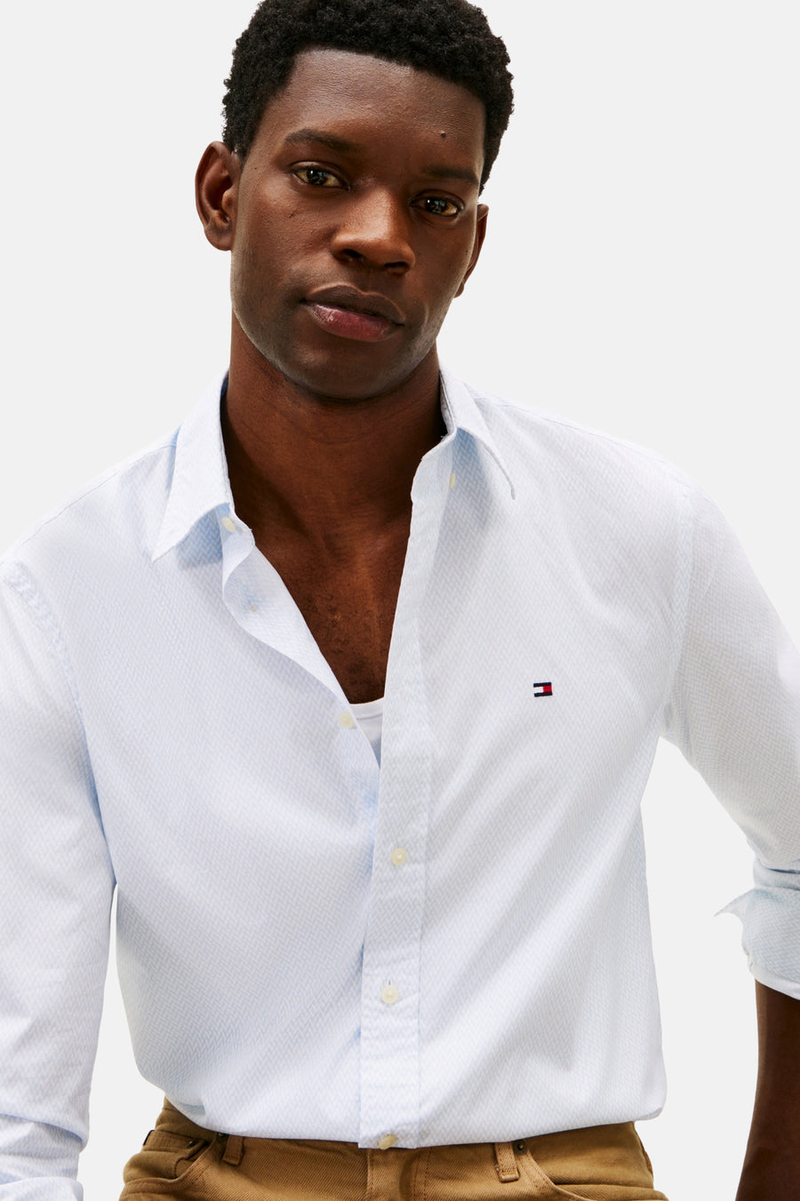 Chemise à manches longues bleue à motifs, de TOMMY HILFIGER, portée avec un pantalon marron.