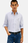Chemise à manches longues bleue de TOMMY HILFIGER, motif discret, portée avec un jean bleu et une ceinture noire.
