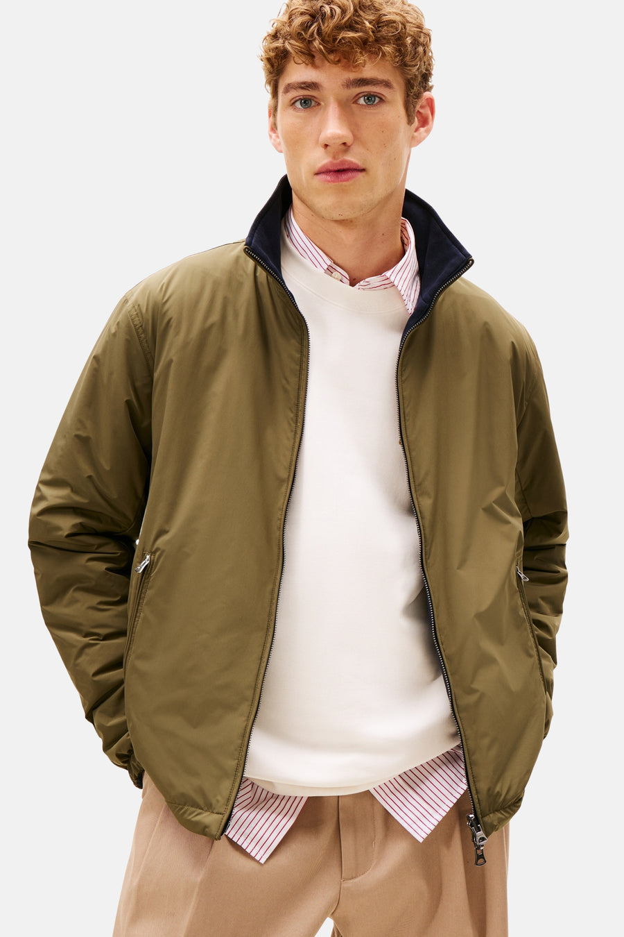 Kaki regenjas van Tommy Hilfiger, gedragen met een witte trui en een wijde beige broek.