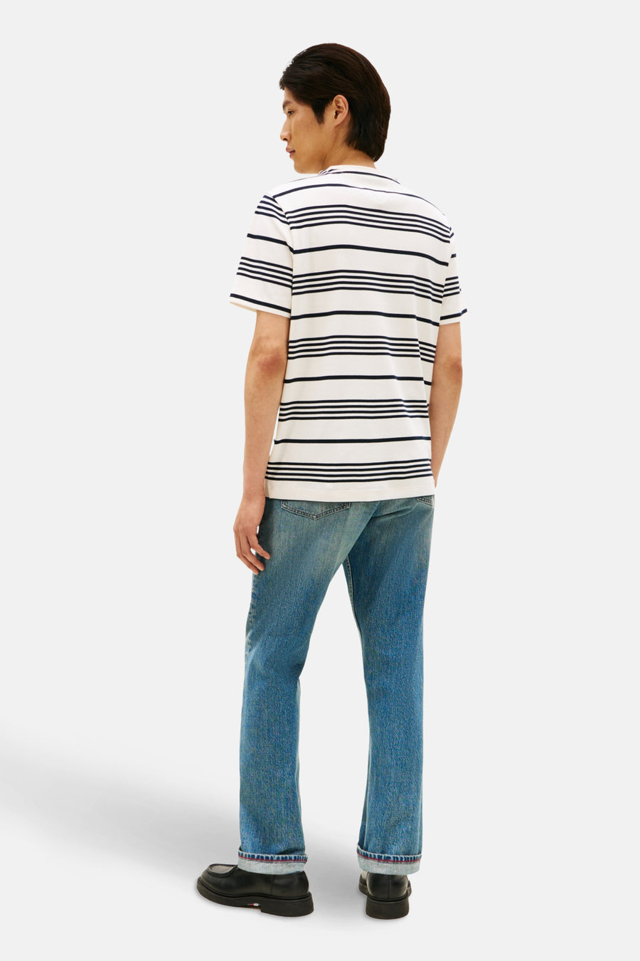 T-shirt à manches courtes écru de TOMMY HILFIGER, rayures horizontales bleu marine, porté avec un jean bleu et des chaussures noires, vue de dos.