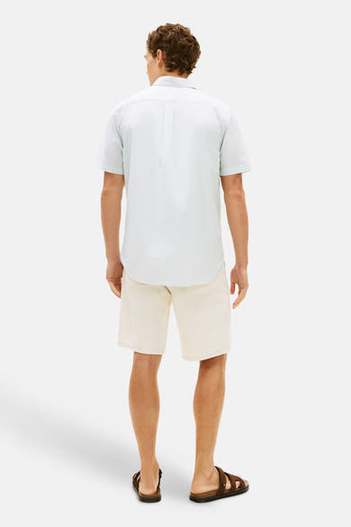 Wit gestreept overhemd met korte mouwen van Tommy Hilfiger, van achteren gezien, gedragen met een beige korte broek en bruine sandalen