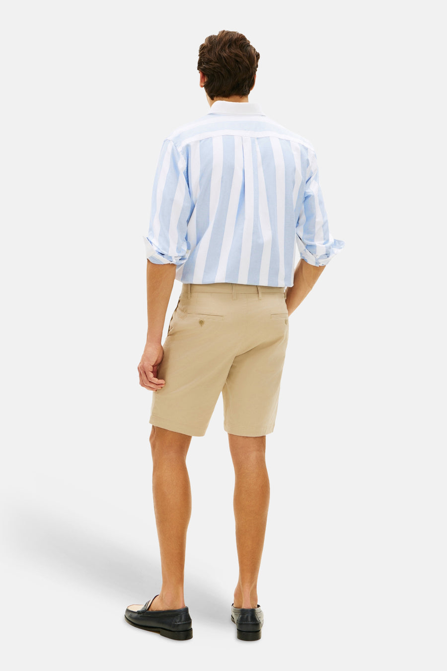 Bermuda beige de TOMMY HILFIGER, porté avec une chemise rayée bleu et blanche et des mocassins en cuir noir.