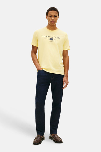 T-shirt jaune à manches courtes de TOMMY HILFIGER, avec logo imprimé sur le devant, porté avec un jean bleu et des mocassins.