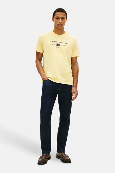T-shirt jaune à manches courtes de TOMMY HILFIGER, avec logo imprimé sur le devant, porté avec un jean bleu et des mocassins.