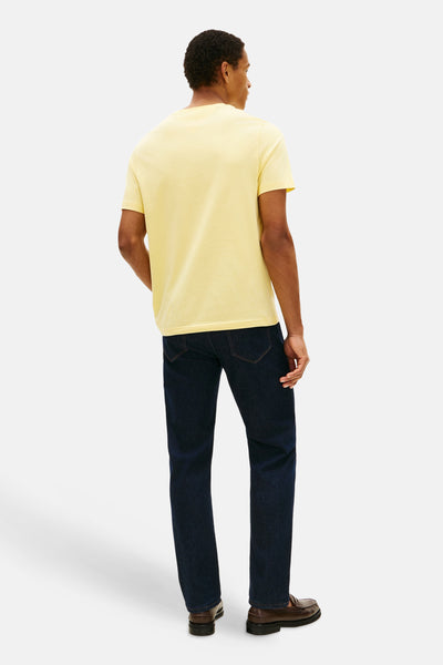 Gele T-shirt met korte mouwen van TOMMY HILFIGER, gedragen met een donkerblauwe jeans en bruine leren loafers.