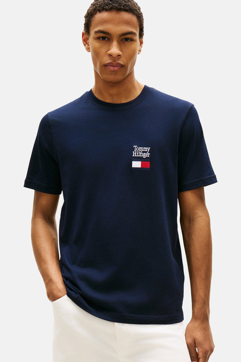 Blauw T-shirt met korte mouwen van TOMMY HILFIGER met vlaglogo op de borst, gedragen met gebroken witte broek.