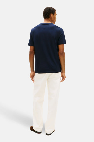 Blauwe T-shirt met korte mouwen van TOMMY HILFIGER, van achteren gezien, gedragen met een witte broek en bruine schoenen.