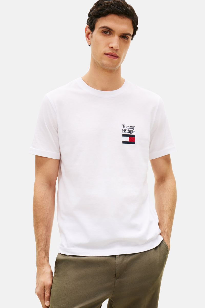 Wit T-shirt met korte mouwen van TOMMY HILFIGER, met geborduurd logo op de borst, gedragen met een zwarte broek en schoenen.