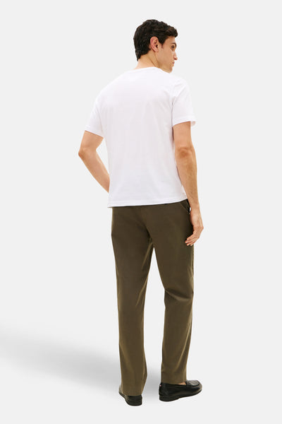 Witte T-shirt met korte mouwen van TOMMY HILFIGER, gedragen met een olijfgroene broek en zwarte loafers, achtergezicht.