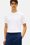 T-shirt blanc à manches courtes de TOMMY HILFIGER avec un logo discret sur la poitrine, porté avec un pantalon bleu marine.