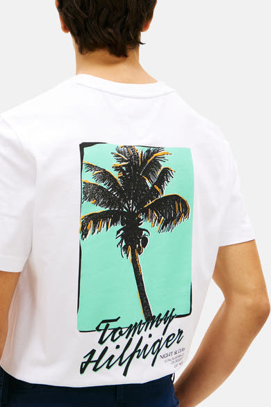 T-shirt blanc de TOMMY HILFIGER, dos imprimé d'un palmier noir avec reflets jaunes sur fond vert menthe et logo.