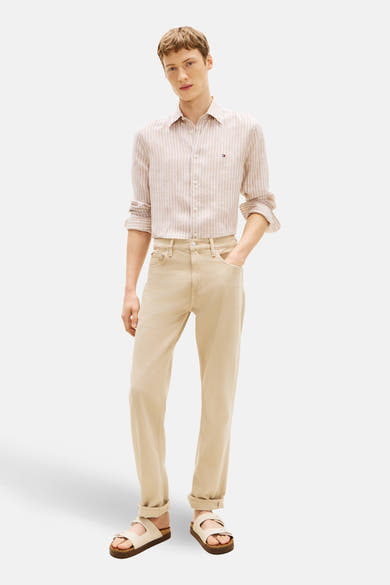 Chemise à manches longues beige à rayures, de TOMMY HILFIGER, portée avec un pantalon beige et des sandales.