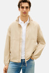Veste beige de TOMMY HILFIGER, portée sur un polo blanc avec un jean bleu.