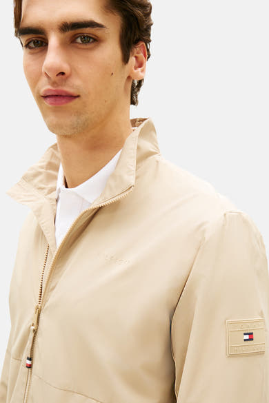 Veste beige de Tommy Hilfiger avec fermeture éclair et écusson logo sur la manche