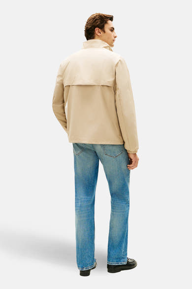 Veste beige de TOMMY HILFIGER, portée avec un jean bleu et des chaussures noires, vue de dos.
